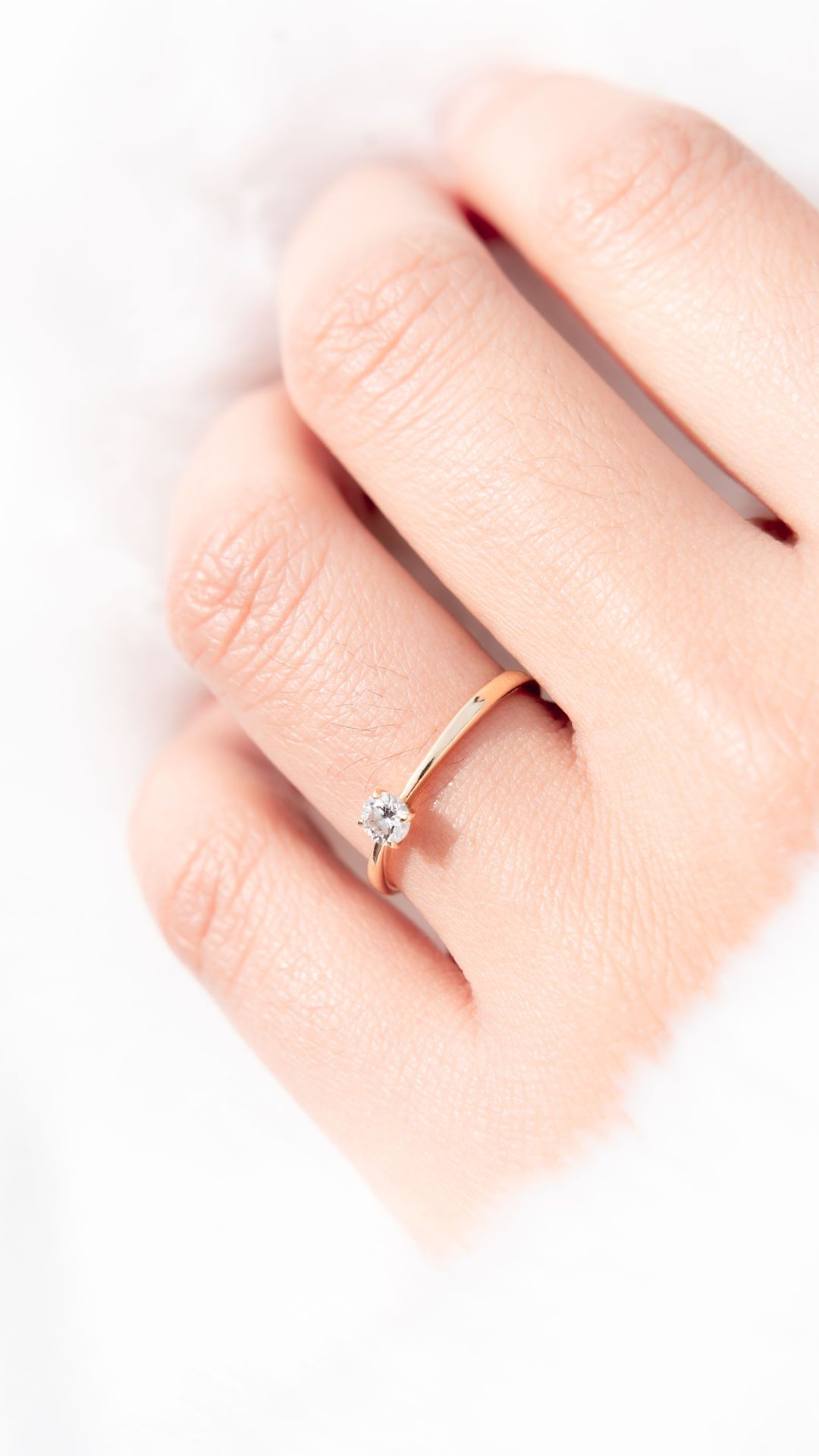 Anillo solitario de oro en mano